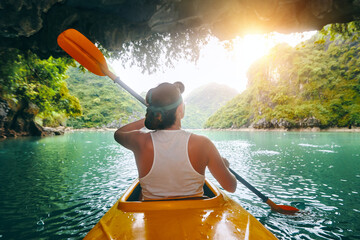 Woman paddling kayak inside from cave in beautiful Ha Long bay. Vietnam.