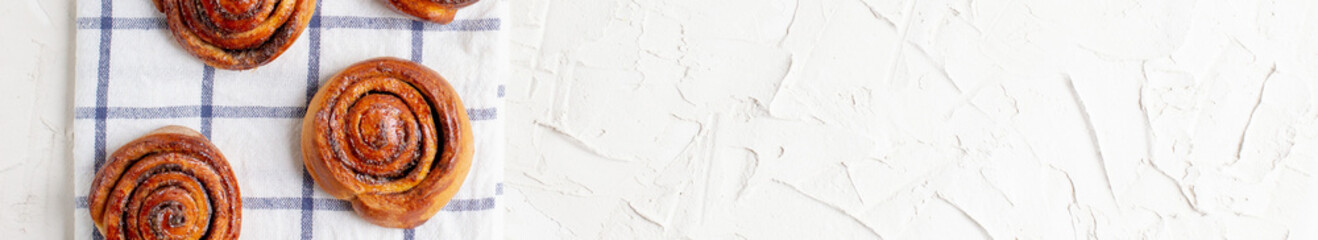 banner of baked cinnamon buns on light background with checkered napkin