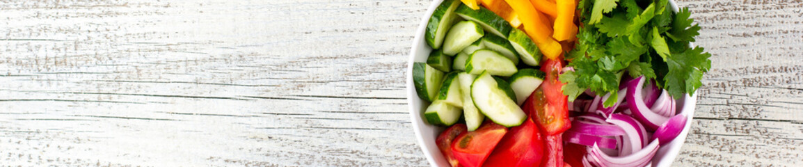 banner of Plate of rainbow salad with different vegetables and herbs in white bowl on white wooden background