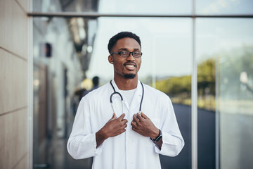 Obraz premium Portrait of an African doctor looking at camera and smiling in front of clinic