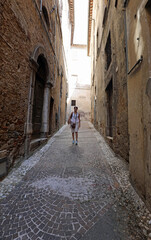 tourist woman walking through the narrow alleys of the ancient city in Italy in summer