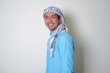 Side view of young Asian man wearing Arabian shemagh head scarf smiling friendly