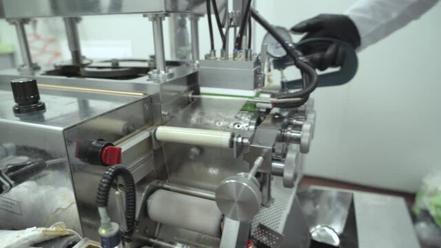 Scientist hand in black glove pushing softgel capsules using Air compressor gun 