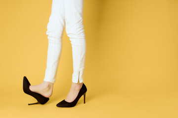 inverted female legs in black shoes posing yellow background