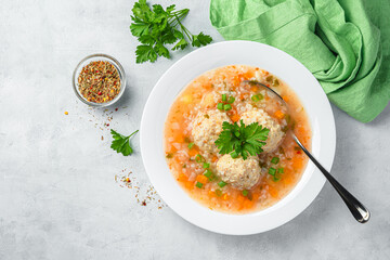 Soup with turkey meat meatballs and vegetables on a gray background.