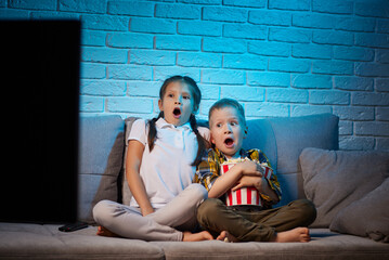 two children with remote control watching TV