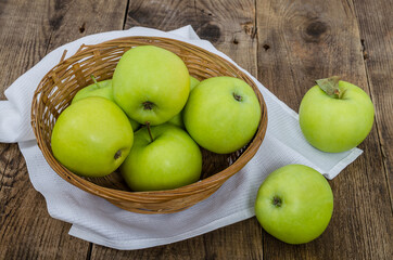 Ripe green apples in a wicker bowl
