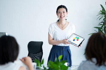 チームメンバーにプレゼンテーションをする女性