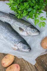 Two trout with potatoes and parsley on wooden table