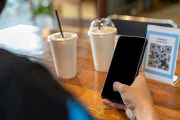 Men use phones to scan a qr code to select a menu or scan to receive a discount or pay for food and drink inside a cafe. using the phone to transfer money or pay online without cash concept.