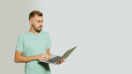 Young man posing isolated on white background studio portrait. People lifestyle concept. Mock up copy space. Holding and working on laptop pc computer.