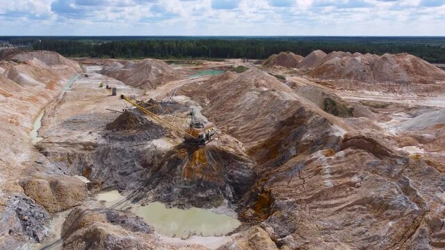 Boom walking excavator digs ilmenite ore in quarry, aerial view