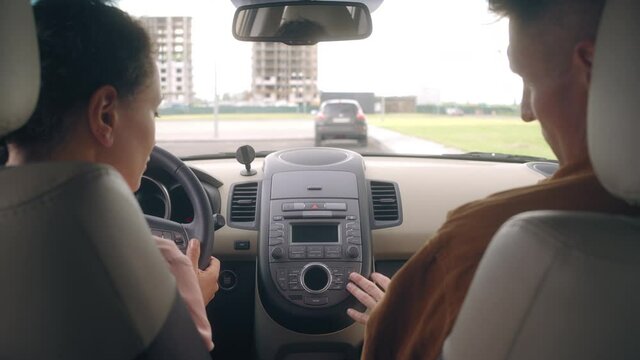 Driving instructor talking to woman in the car, explaining how to operate auto