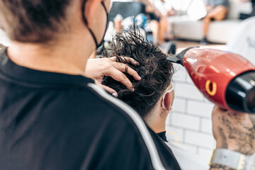 Hairdresser drying the hair of a client with mask
