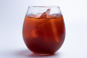 Thai style iced tea in a round clear glass on a white background.