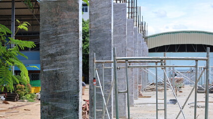 Concrete posts wrapped in plastic. Concrete curing retains moisture in the column hardening to...
