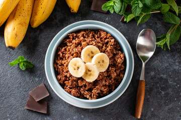 Chocolate oatmeal with banana - healthy vegetarian breakfast on a grey background, top view. Flat lay