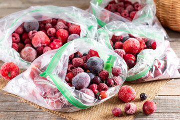 Frozen berries: black currant, red currant, blackberry, blueberry, raspberry, strawberry, cherry, plum in a plastic bag on a table. Frozen food.