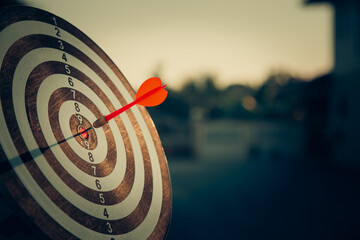 bullseye target or dart board has red dart arrow throw hitting the center of a shooting for...