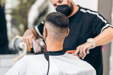 Fototapeta premium Selective focus on the shaved nape of a man with mask in a barbershop