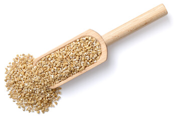 raw steel cut oats in the wooden scoop, isolated on the white background, top view