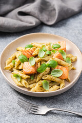 Penne pasta with baked salmon, pesto and fresh basil, close-up view