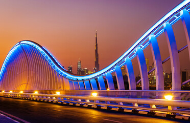 Beautiful view of Meydan Bridge in Dubai. Modern artistic bridge in Dubai. Night architectural shot of a bridge with curvy blue lights.