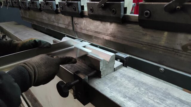 Bending a thick sheet of metal on a bending machine, close-up. Machine operator bends a sheet metal.