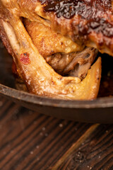 Pieces of roast duck with spices in a frying pan, close-up, selective focus.