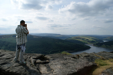 Obraz premium photographer taking photo on Bamford edge, looking out over the Ladybower Reservoir, Derwent Valley in Derbyshire, England