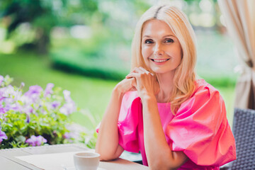 Fototapeta premium Photo portrait elder woman beautiful attractive with blonde hair sitting in cafe wearing pink dress
