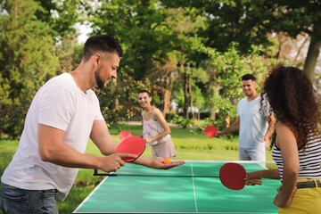 Friends playing ping pong outdoors on summer day - obrazy, fototapety, plakaty