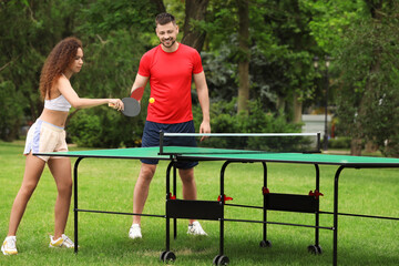 Friends playing ping pong outdoors on summer day - obrazy, fototapety, plakaty