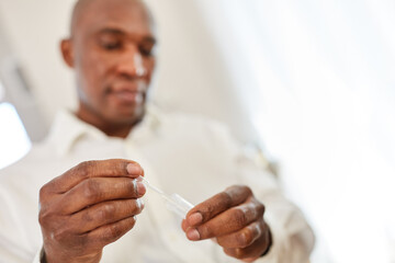 Afrikanischer Mann macht Coronavirus Selbsttest mit Speichelprobe