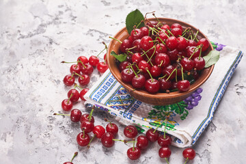 Bowl with red cherry on gray background, top view