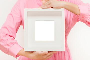 white art frame held by anonymous woman in pink dress