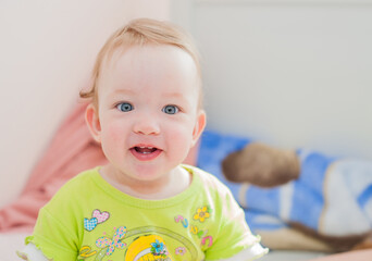 Full length of a baby girl smiling while sitting on the bed at home. Child, happiness and people concept - adorable baby - 457499669