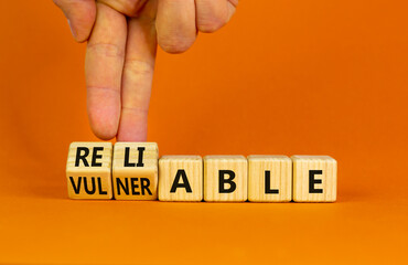 Vulnerable or reliable symbol. Businessman turns wooden cubes and changes the word Vulnerable to...