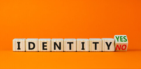 Identity symbol. Turned a wooden cube and changed words 'identity no' to 'identity yes'. Beautiful orange background. Business and identity concept, copy space.