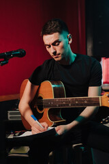 Songwriter thinking and writing notes, lyrics on sheets at studio. Concept for musician creative,...