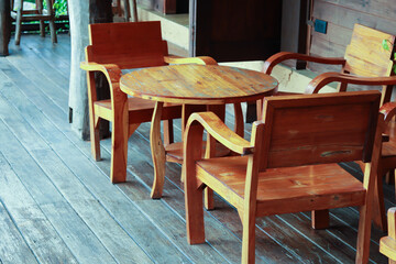 Wood furniture in wooden house. Table has round shape with set of wood arm chair.