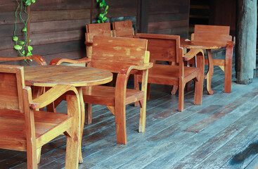 Wood furniture in wooden house. Table has round shape with set of wood arm chair.