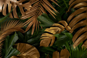 Creative nature background. Gold and green tropical Monstera and palm leaves. Minimal summer...