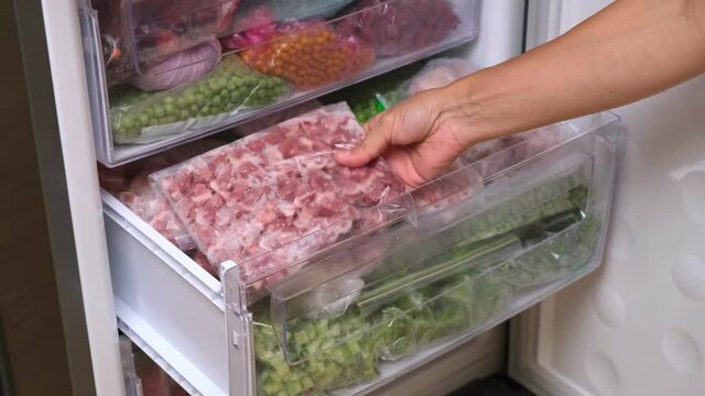 Frozen pork meat which has been vacuum sealed inside a fridge freezer. Home stock shelf. Frozen food
