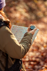 Woman using compass and map while hiking in the forest