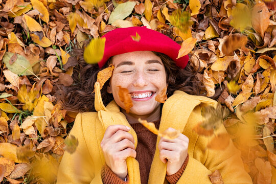 Playful woman lying on autumn leaves at park