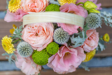 A basket of beautiful flowers, pastel colors,  for the wedding party, placed on a wooden park bench with a blurry green background. Space for text. flowers shop or flowers delivery. mother's day