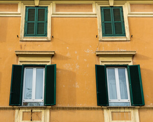 Fototapeta na wymiar Open and closed window shutters of an old building in Rome, Italy