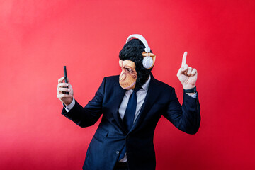 Businessman in monkey mask dancing with headphones and smartphone