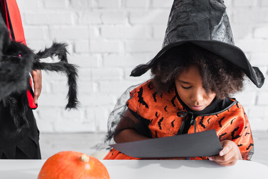 African American Kid Holding Black Paper Near Brother With Toy Spider